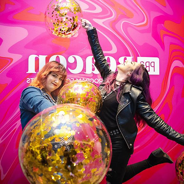 http://ijd7.thestudioentrance.com/wp-content/uploads/2023/06/two-women-holding-balloons-in-front-of-a-pink-pba-beacon-wall.jpg